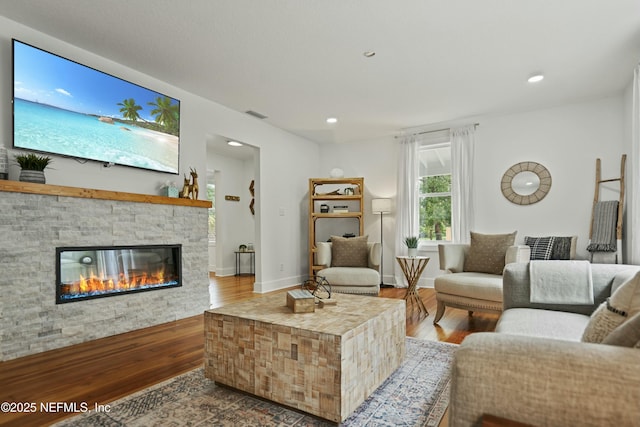 living room with hardwood / wood-style flooring and a stone fireplace