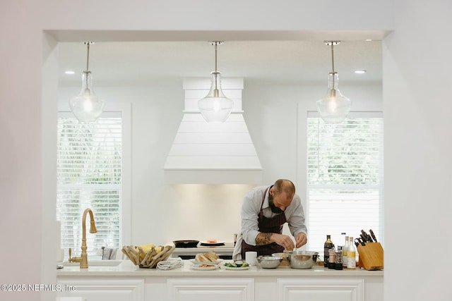 bar with sink, white cabinets, and decorative light fixtures