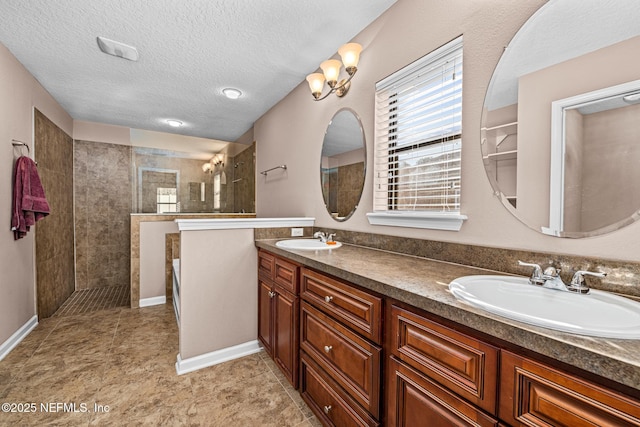 bathroom with tiled shower, vanity, and a textured ceiling