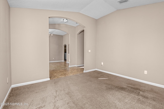 empty room with vaulted ceiling, carpet floors, and a textured ceiling