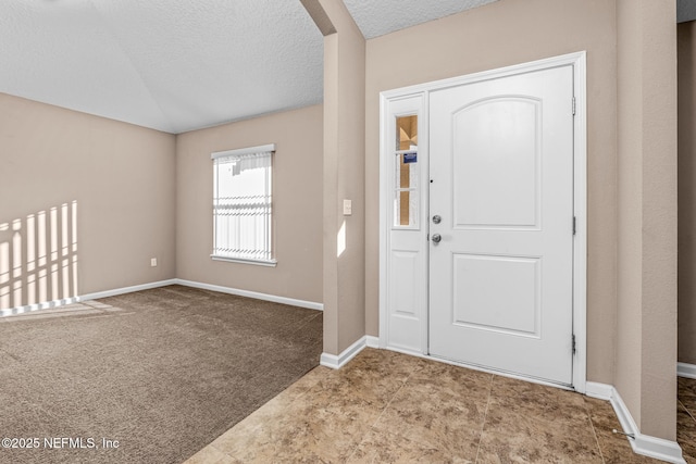 entrance foyer with lofted ceiling, light carpet, and a textured ceiling