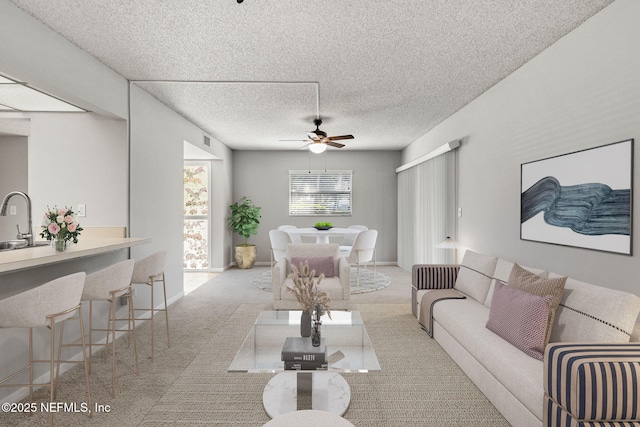 living room with ceiling fan, sink, and a textured ceiling