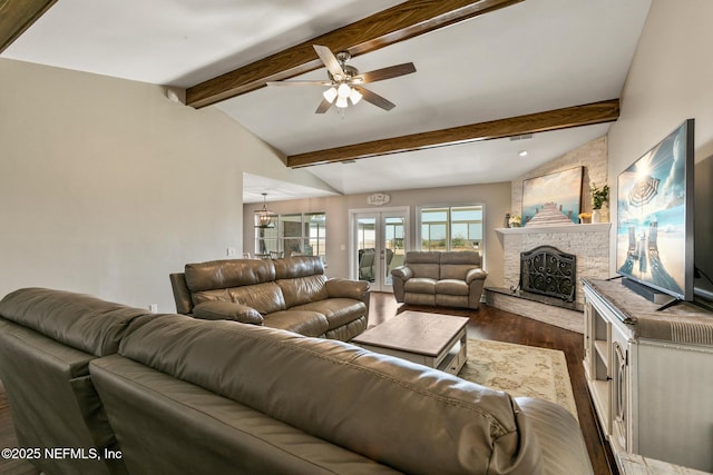 living room with ceiling fan, dark hardwood / wood-style floors, lofted ceiling with beams, a stone fireplace, and french doors