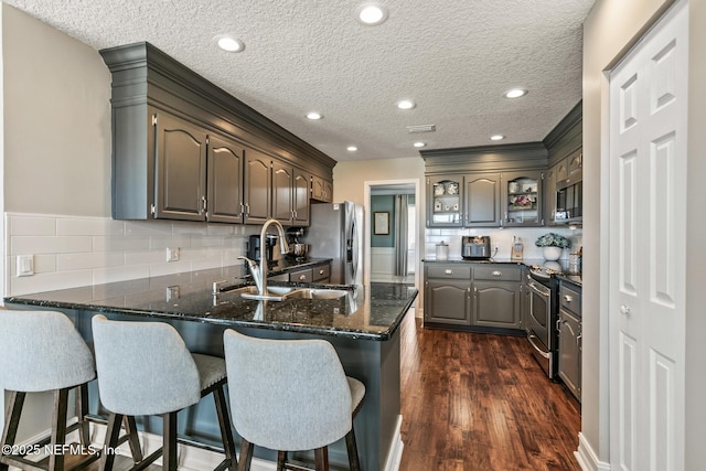 kitchen featuring sink, dark hardwood / wood-style floors, kitchen peninsula, stainless steel appliances, and backsplash