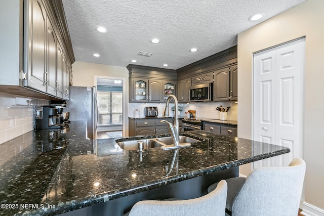 kitchen with sink, a kitchen bar, kitchen peninsula, and appliances with stainless steel finishes