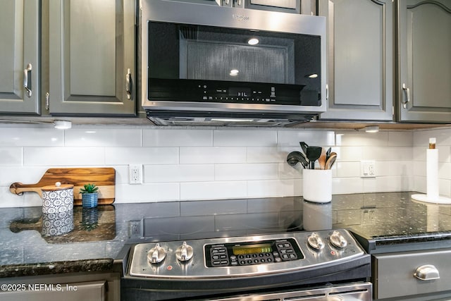 kitchen with dark stone countertops, gray cabinets, tasteful backsplash, and appliances with stainless steel finishes