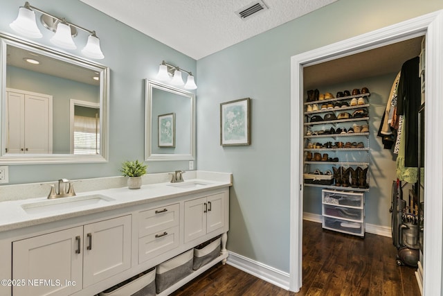 bathroom featuring vanity, wood-type flooring, and a textured ceiling