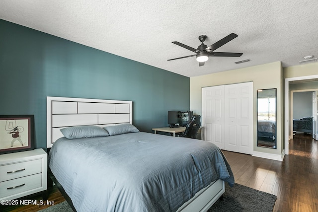 bedroom with ceiling fan, dark hardwood / wood-style floors, a textured ceiling, and a closet