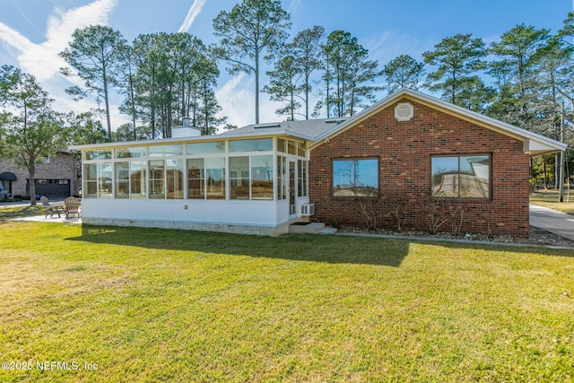 rear view of house with a sunroom and a lawn