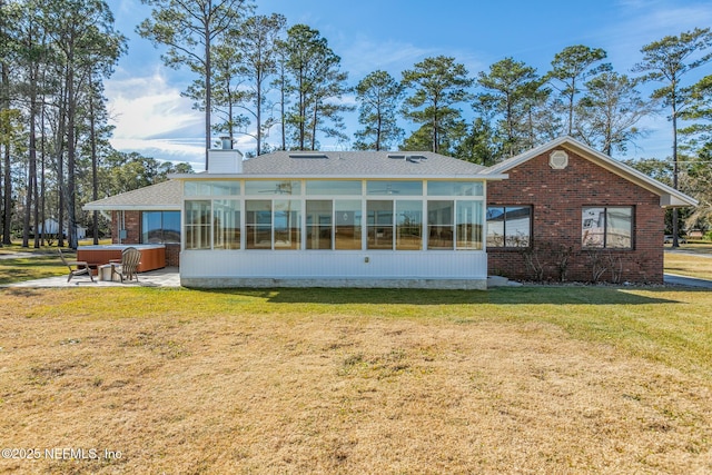 rear view of house featuring a hot tub, a patio, a sunroom, and a lawn