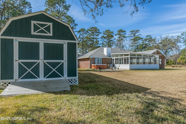 view of outbuilding with a yard, a hot tub, and a sunroom