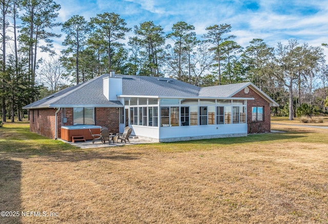 rear view of property with a yard, a hot tub, a patio area, and a sunroom