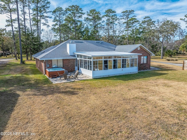 back of property with a patio area, a sunroom, a hot tub, and a lawn