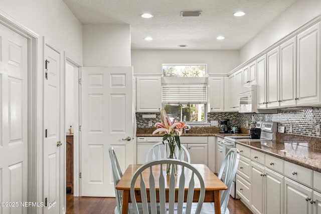 kitchen featuring white appliances, dark wood-type flooring, backsplash, white cabinets, and dark stone counters