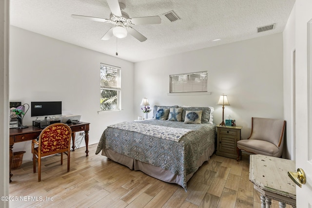 bedroom featuring ceiling fan, light hardwood / wood-style floors, and a textured ceiling