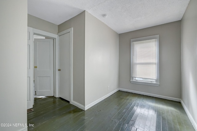 spare room with a textured ceiling and dark hardwood / wood-style flooring