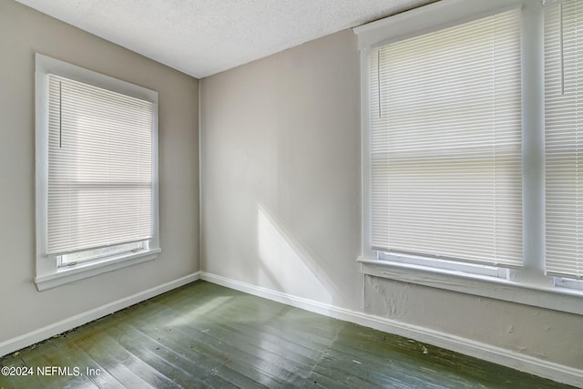 unfurnished room with dark wood-type flooring and a textured ceiling