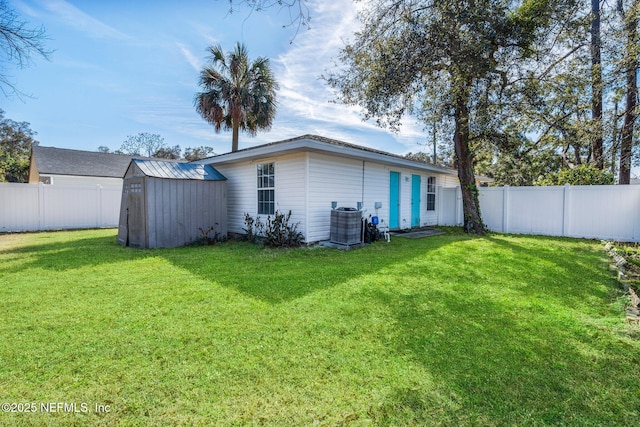 back of property featuring a shed, a yard, and central air condition unit