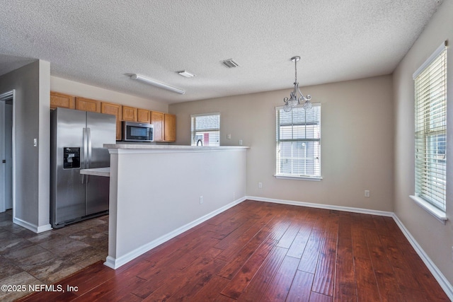 kitchen featuring pendant lighting, dark hardwood / wood-style flooring, kitchen peninsula, stainless steel appliances, and an inviting chandelier