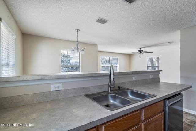 kitchen with sink, decorative light fixtures, stainless steel dishwasher, and a textured ceiling