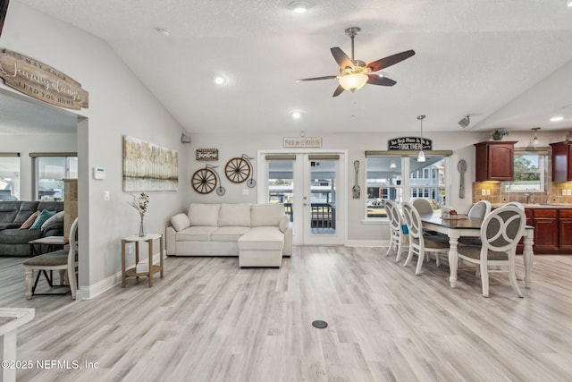 living room with ceiling fan, lofted ceiling, light hardwood / wood-style flooring, and a textured ceiling