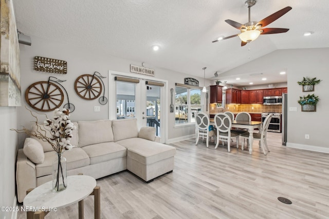 living room featuring lofted ceiling, french doors, a textured ceiling, and light wood-type flooring