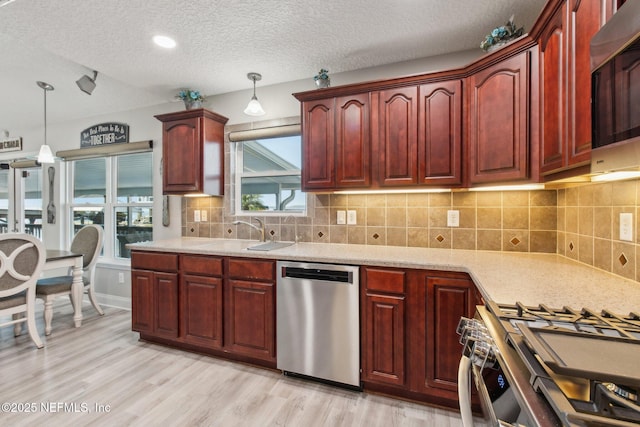 kitchen featuring sink, tasteful backsplash, hanging light fixtures, light wood-type flooring, and stainless steel appliances