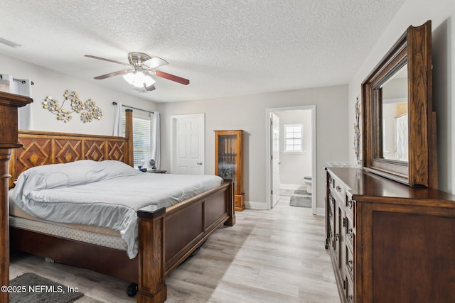 bedroom with ensuite bathroom, a textured ceiling, ceiling fan, and light hardwood / wood-style flooring