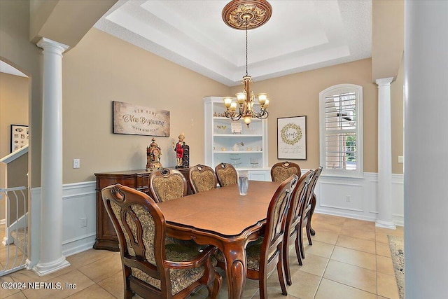 tiled dining area featuring ornate columns, a raised ceiling, and a chandelier