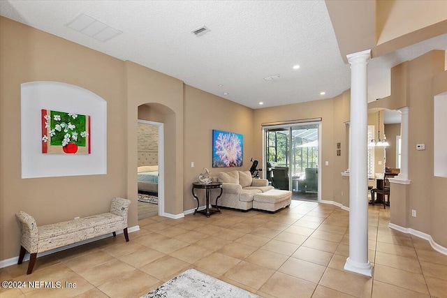 living room with light tile patterned flooring, decorative columns, and a textured ceiling