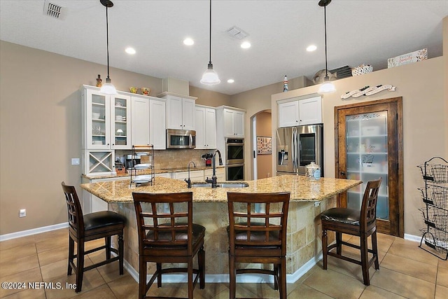 kitchen featuring pendant lighting, stainless steel appliances, and a large island with sink