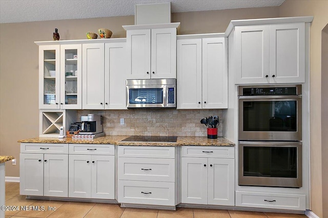 kitchen featuring white cabinetry, backsplash, light stone counters, and stainless steel appliances