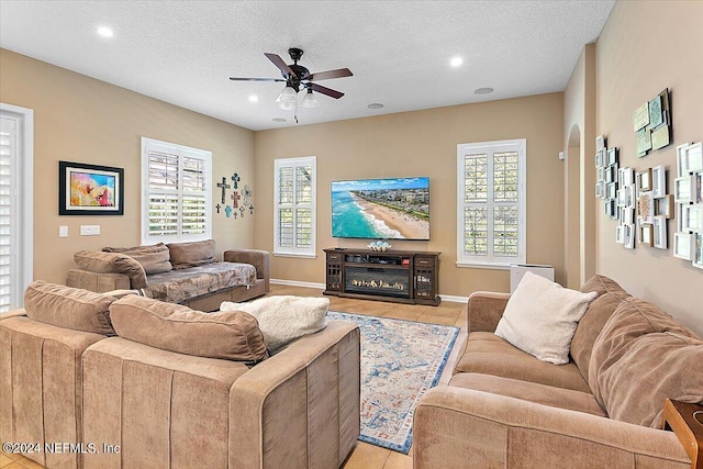 tiled living room featuring ceiling fan and a textured ceiling