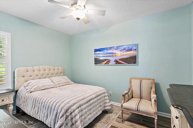 bedroom featuring ceiling fan, wood-type flooring, and a textured ceiling