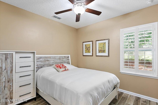 bedroom featuring ceiling fan, dark wood-type flooring, and a textured ceiling