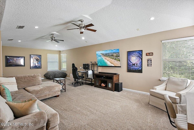 carpeted living room featuring ceiling fan and a textured ceiling