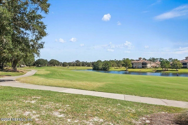 surrounding community with a water view and a yard