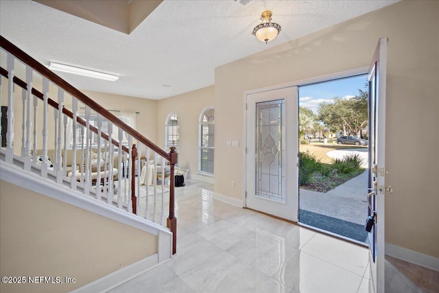 foyer entrance featuring light tile patterned floors and a textured ceiling