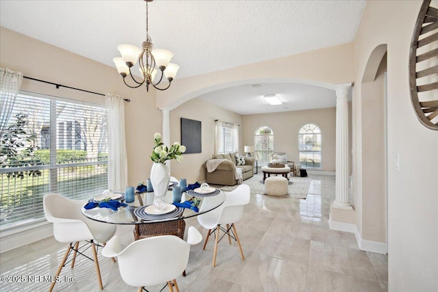 dining area featuring an inviting chandelier, decorative columns, and a textured ceiling