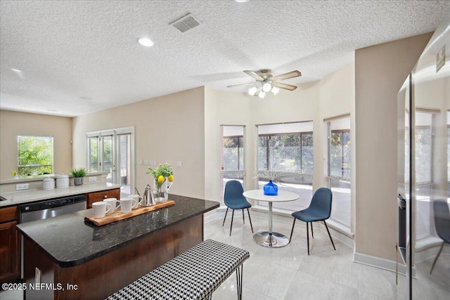 kitchen with dishwasher, a kitchen island, and a textured ceiling