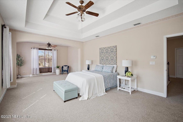 carpeted bedroom featuring ceiling fan and a tray ceiling