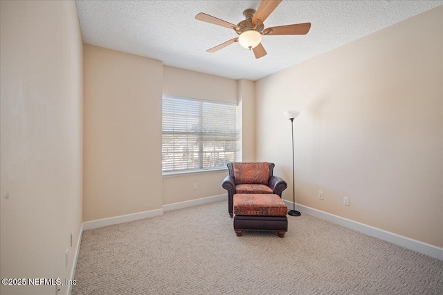 living area with ceiling fan, light colored carpet, and a textured ceiling