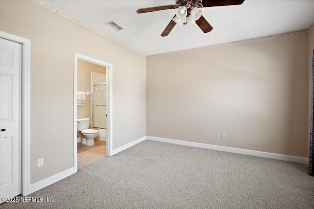 unfurnished bedroom featuring ceiling fan, light colored carpet, a textured ceiling, and ensuite bathroom