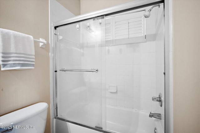 bathroom featuring toilet and combined bath / shower with glass door