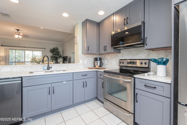 kitchen featuring sink, crown molding, backsplash, stainless steel appliances, and light tile patterned flooring