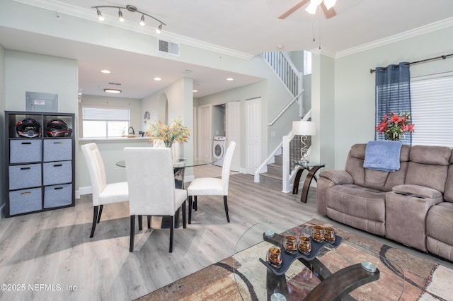 dining room featuring crown molding, light hardwood / wood-style flooring, ceiling fan, track lighting, and washer / dryer