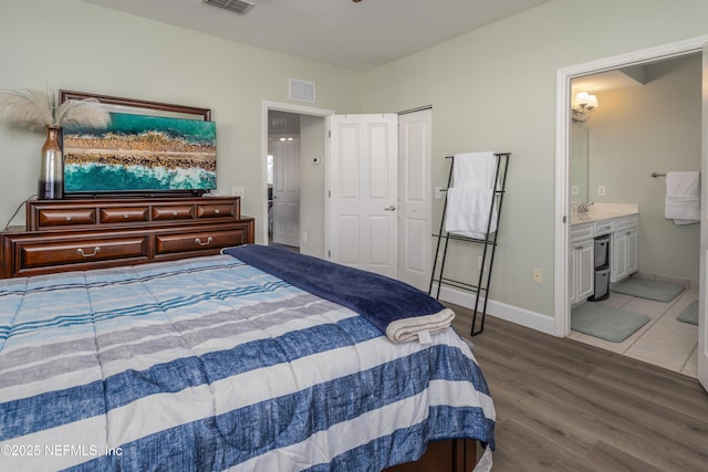 bedroom featuring ensuite bath, wood-type flooring, and a closet