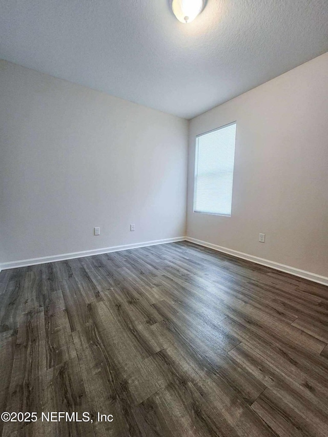 empty room featuring baseboards, a textured ceiling, and dark wood finished floors