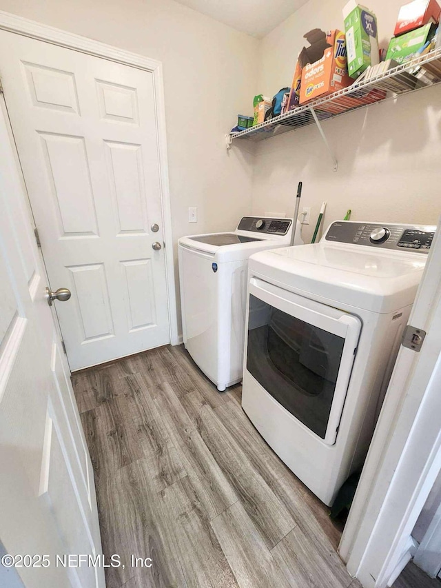 laundry room with laundry area, washing machine and dryer, and light wood-style flooring