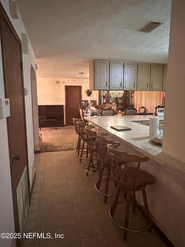 kitchen featuring light tile patterned flooring, a textured ceiling, and kitchen peninsula